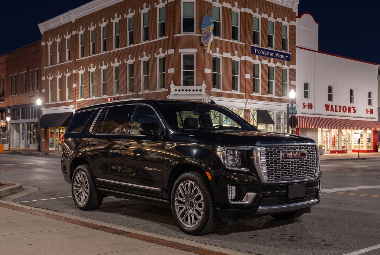 Uploaded black GMC Yukon Denali SUV in an AI-edited downtown Bentonville nighttime setting beside Walton's 5-10